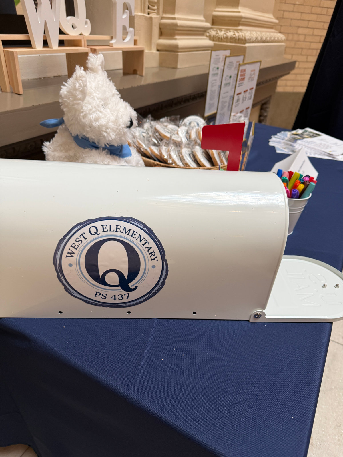 A white mailbox printed with the West Q Elementary PS 437 seal, ready for families’ wishes